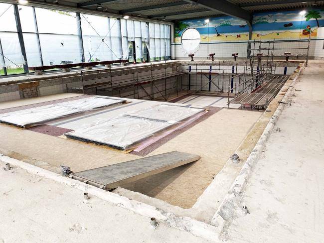 Stadtbad, von innen, die Fliesen sind größtenteils entfernt, im Becken stehen Gerüste, die Springböcke sind eingepackt.
