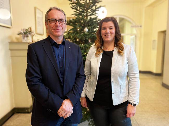 Bürgermeister André Dora und Musikschulleiterin Anne Reckert im Rathausflur vor einem geschmückten Tannenbaum.