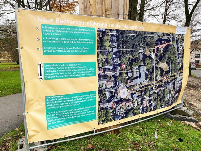 Großes Plakat an einem Bauzaun, das auf die neue Radverkehrsführung an der Hafenstraße hinweist.