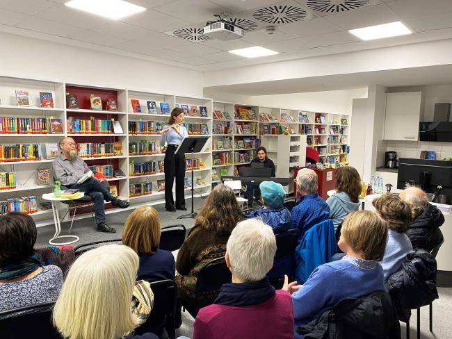 Wolfgang Tänzer und Lehrkräfte der Musikschule beim Konzert mit Lesung in der Stadtbücherei, im Vordergrund das Publikum von hinten.