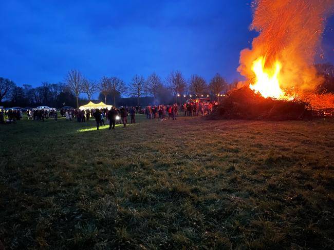 Menschen stehen an einem großen Osterfeuer