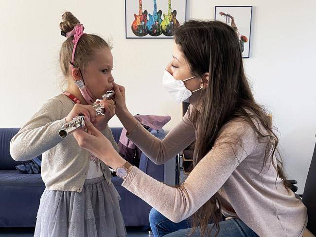 Eine Musikschullehrerin erklärt einem Mädchen, wie man auf der Querflöte spielt.