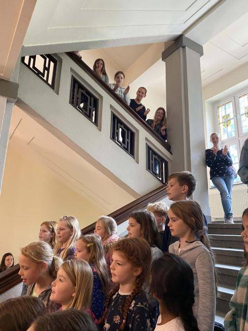 Der Chor der Albert-Schweitzer-Schule steht auf der Treppe - und viele schauen zu.