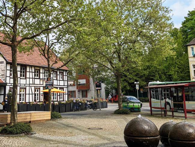 Tigg mit dem Kaffeehaus Köster und der Bushaltestelle, im Vordergrund die Brunnenkugeln