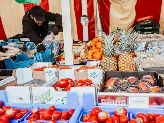 Ein Mann auf dem Wochenmarkt packt die Obst-Wünsche des Kunden ein