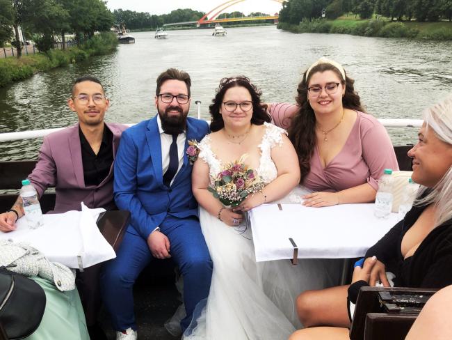 Ein frisch verheiratetes Pärchen auf dem Hecke des Schiffes mit Hochzeitsgästen 