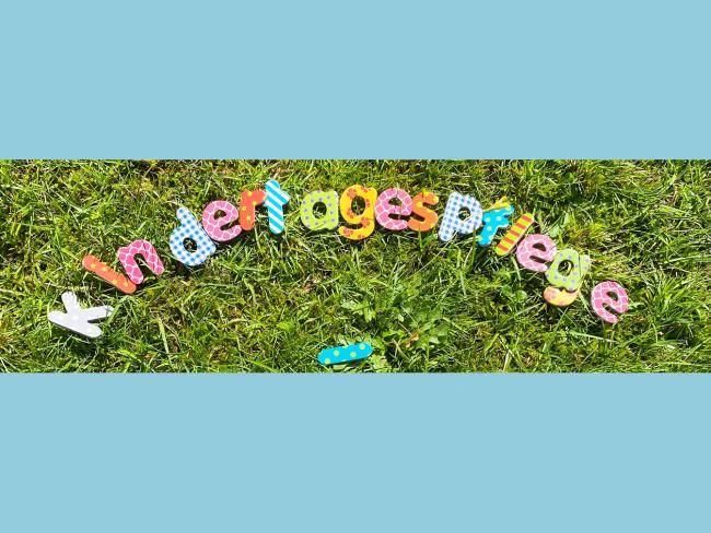 Bunte Buchstaben auf einer Wiese, die das Wort "Kindertagespflege" bilden