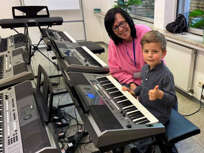 Musikschullehrerin Vera Will mit einem Kind beim Ausprobieren des Keyboards am Tag der Offenen Tür der Musikschule 2024