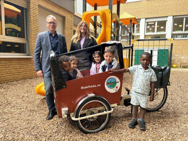 Das Foto zeigt Bürgermeister André Dora und Kita-Leiterin Kim Starschinski am Lastenrad und fünf Kinder des Familienzentrums ARTIKUS