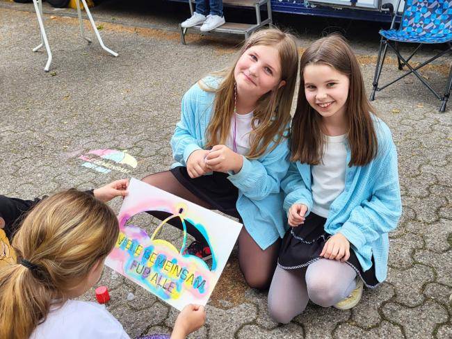 Kinder mit Schablonen "Viele gemeinsam für alle" zum Auftakt der "Woche der Demokratie" am Friedenslabor am Stadtbad