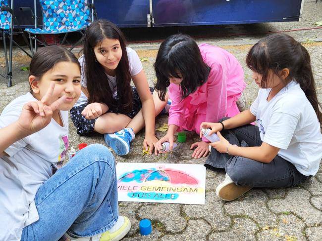 Kinder mit der Schablone "Viele gemeinsam für alle" zum Auftakt der "Woche der Demokratie" am Friedenslabor am Stadtbad