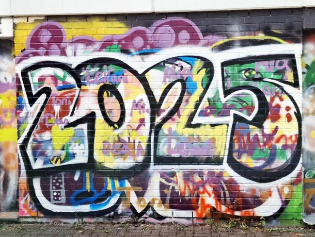 An einer Wand auf dem Außengelände des JaM haben Teilnehmer*innen der Kinderstadt ein Graffiti aufgesprüht.