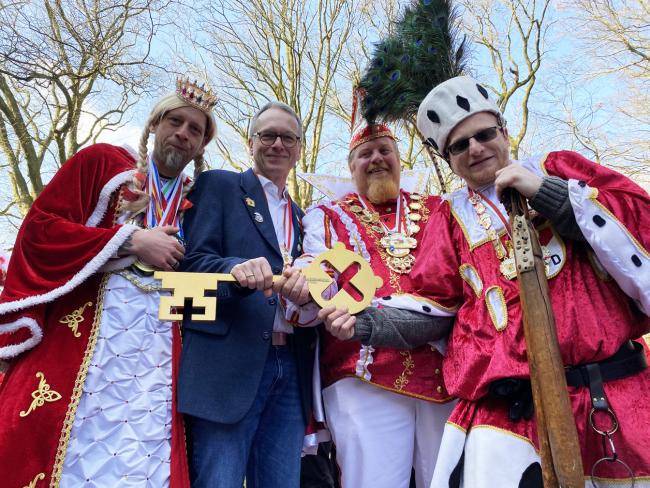 Bürgermeister André Dora übergibt dem Dreigestirn der KG Rot-Weiß 2025 den "Schlüssel" zum Rathaus.SChlüsse 
