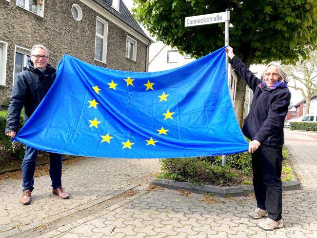 Bürgermeister André Dora und Rosemarie Schloßer mit einer Europafahne an der Cannockstraße