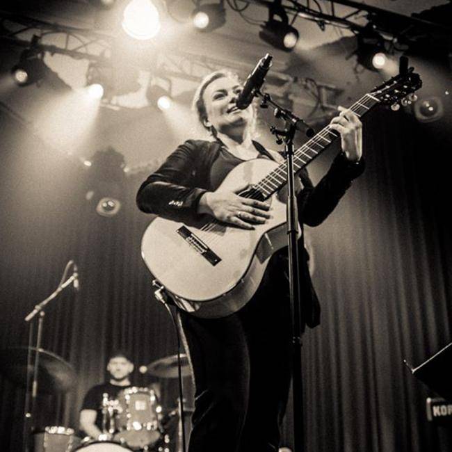Fee Badenius mit Gitarre auf einer Bühne