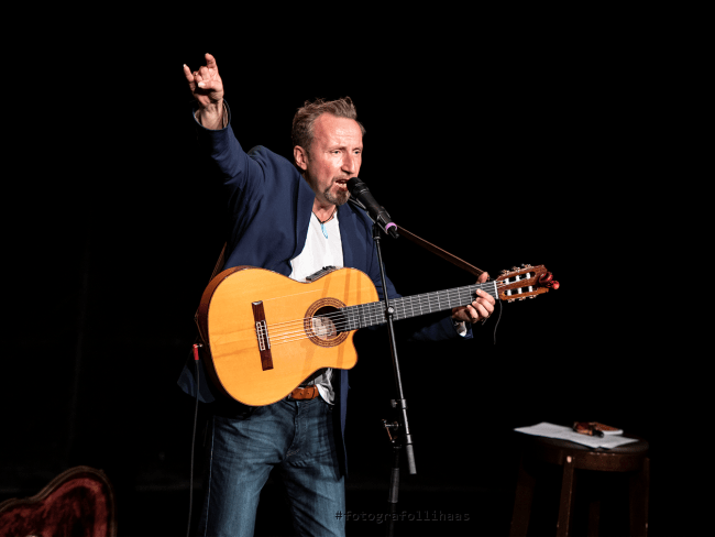 Helmut Sanftenschneider mit Gitarre auf einer Bühne.