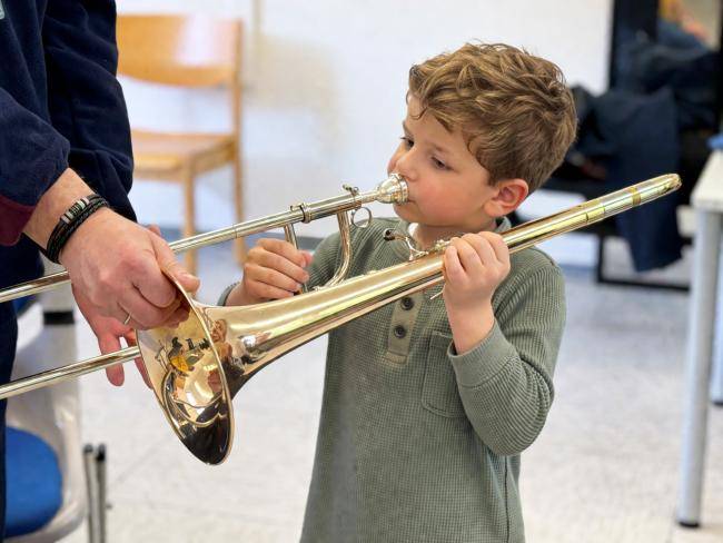 Ein Junge probiert eine Posaune aus.