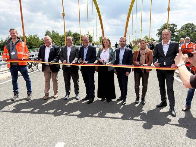 Mehrere Personen schneiden ein schwarz-rot-goldenes Band auf dem Dattelner-Meer-Bogen durch.